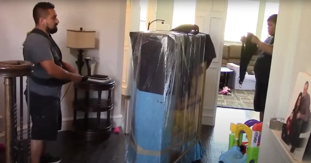 Local Movers 17 Mover next to a shrink-wrapped cabinet in a family room